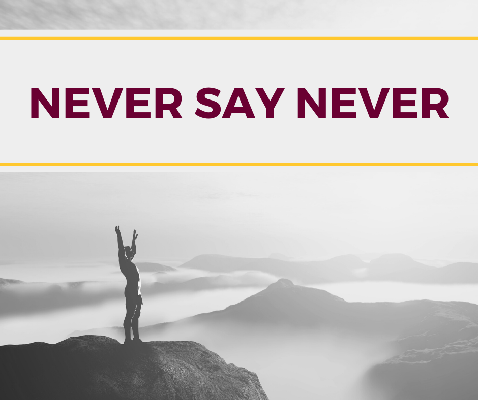 person standing on mountain top with arms raised and never say never text added to the top of the image